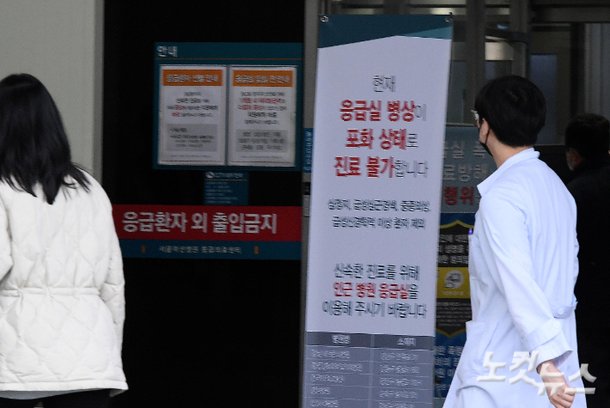 의대 정원 증원 정책에 반발하는 전공의들이 사직서를 제출하며 파업에 돌입한 첫날인 20일 오후 서울의 한 대형병원에서 응급실 병상 포화 안내문 앞으로 의료진이 지나가고 있다. 박종민 기자