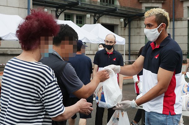 닐손 주니어가 9일 오후 구 서울역사 앞에서 노숙인들에게 마스크와 라면, 생수 등이 담긴 비닐봉지를 나눠주는 모습. 그는 지난 5월부터 매달 노숙인들을 돕는 봉사 활동을 하고 있다. /고운호 기자