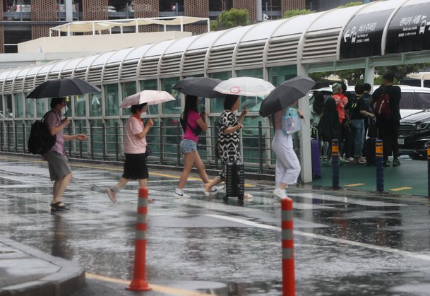 장맛비가 내린 25일 제주도 제주국제공항에서 관광객들이 우산을 쓰고 이동하고 있다 ./연합뉴스