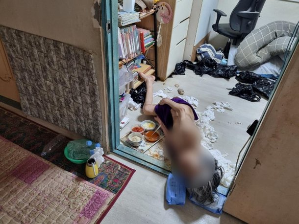 골반 수술 후 제대로 치료받지 못한 &#65279;강영순(가명&#8231;84) 할머니는 벌거벗은 채로 방바닥에 누워서 생활했다. 그의 주변에 대소변이 묻은 휴지와 김치, 밥이 놓여 있다. /이랜드복지재단