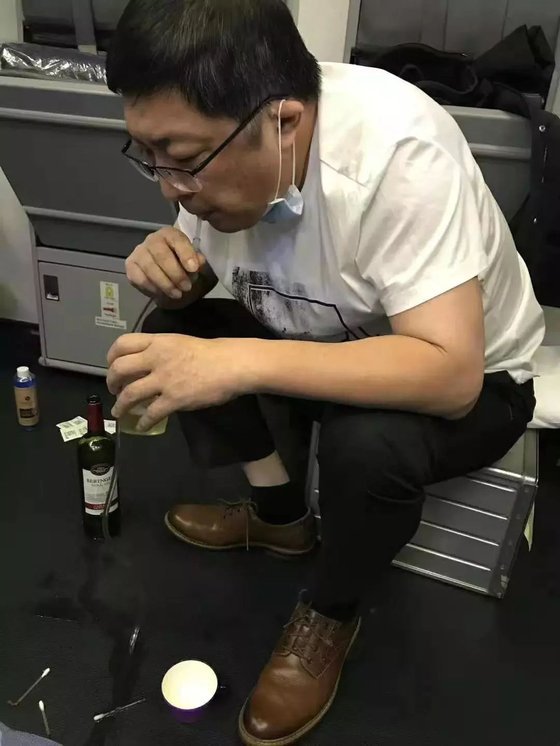 중국 의사 장훙이 중국에서 미국으로 가는 비행기 안에서 소변을 배출하지 못하는 환자의 오줌을 입으로 받아 배출하고 있다. [중국 환구망 캡처]