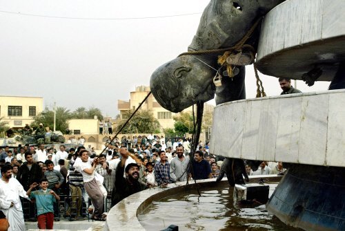2003년 4월 6일 이라크 수도 바그다드 남쪽 110㎞ 거리에 위치한 카르발라 시민들이 미군의 도움을 받아 사담 후세인의 동상을 끌어내리고 있다. [로이터=뉴시스]