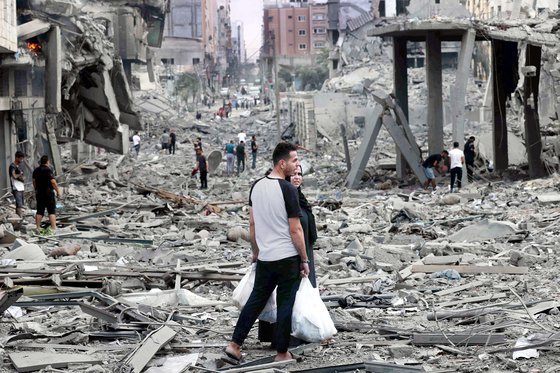 지난 10일 폭격으로 폐허가 된 가자지구에서 팔레스타인 남성과 여성이 대화를 나누고 있다. AFP=연합뉴스