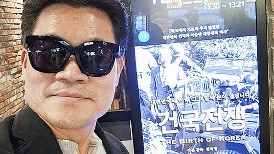 한국사 ‘일타 강사’ 전한길씨가 영화 ‘건국전쟁’을 관람한 뒤 홍보물 앞에서 사진을 찍고 있다. 사진 유튜브 커뮤니티 캡처
