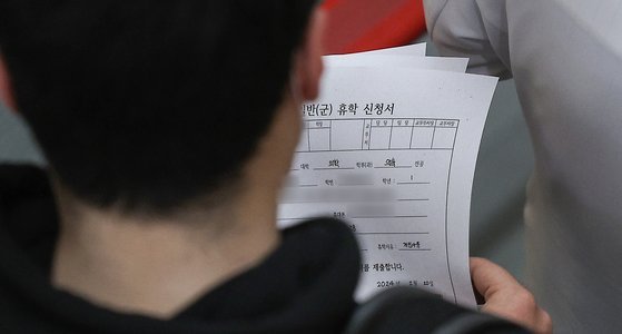 20일 대구 한 대학병원에서 의대생이 휴학 신청서 여러 장을 들고 의사 선배를 따라가고 있다. 연합뉴스