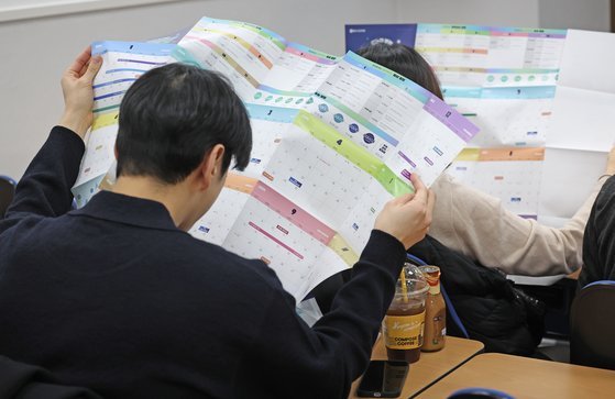 지난 13일 서울의 한 입시학원에서 열린 의대 증원에 따른 입시 판도 분석 설명회에서 학생과 학부모들이 2025 입시 일정표를 보고 있다. 연합뉴스