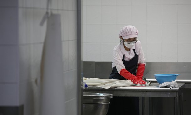 한 급식 조리사가 조리 때 쓴 방수 앞치마를 손세탁하고 있다. 급식실 앞치마는 전부 손으로 세탁해야 한다. 권도현 기자