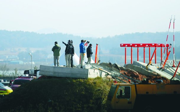 국토교통부 항공철도사고조사위원회와 미국 교통안전위원회NTSB, 연방항공청FAA, 보잉 등 관계자들로 구성된 한·미 합동조사단이 1일 전남 무안군 무안국제공항에서 활주로 로컬라이저착륙유도시설가 설치돼 있는 둔덕에 올라 조사를 벌이고 있다. 뉴시스